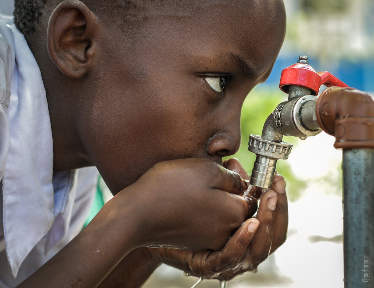 Close-up of a child drinking water from a faucet in Mwanza, Tanzania.